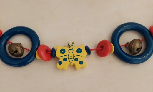 Kinderwagenkette aus Holz mit Schmetterling und Glöckchen