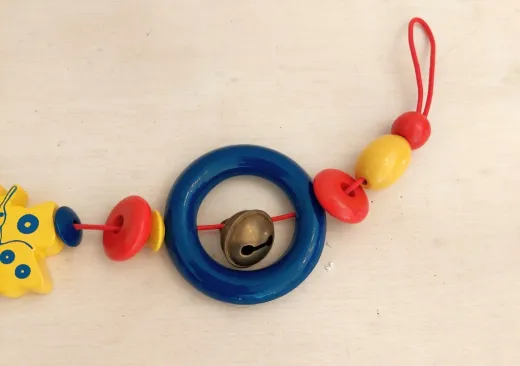 Kinderwagenkette aus Holz mit Schmetterling und Glöckchen